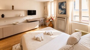 Una habitación de hotel moderna con cama, escritorio, televisor y ventana con cortinas.