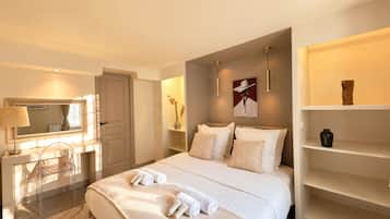 Una habitación de hotel con una cama, un escritorio, una silla, un espejo y una estantería con objetos decorativos.