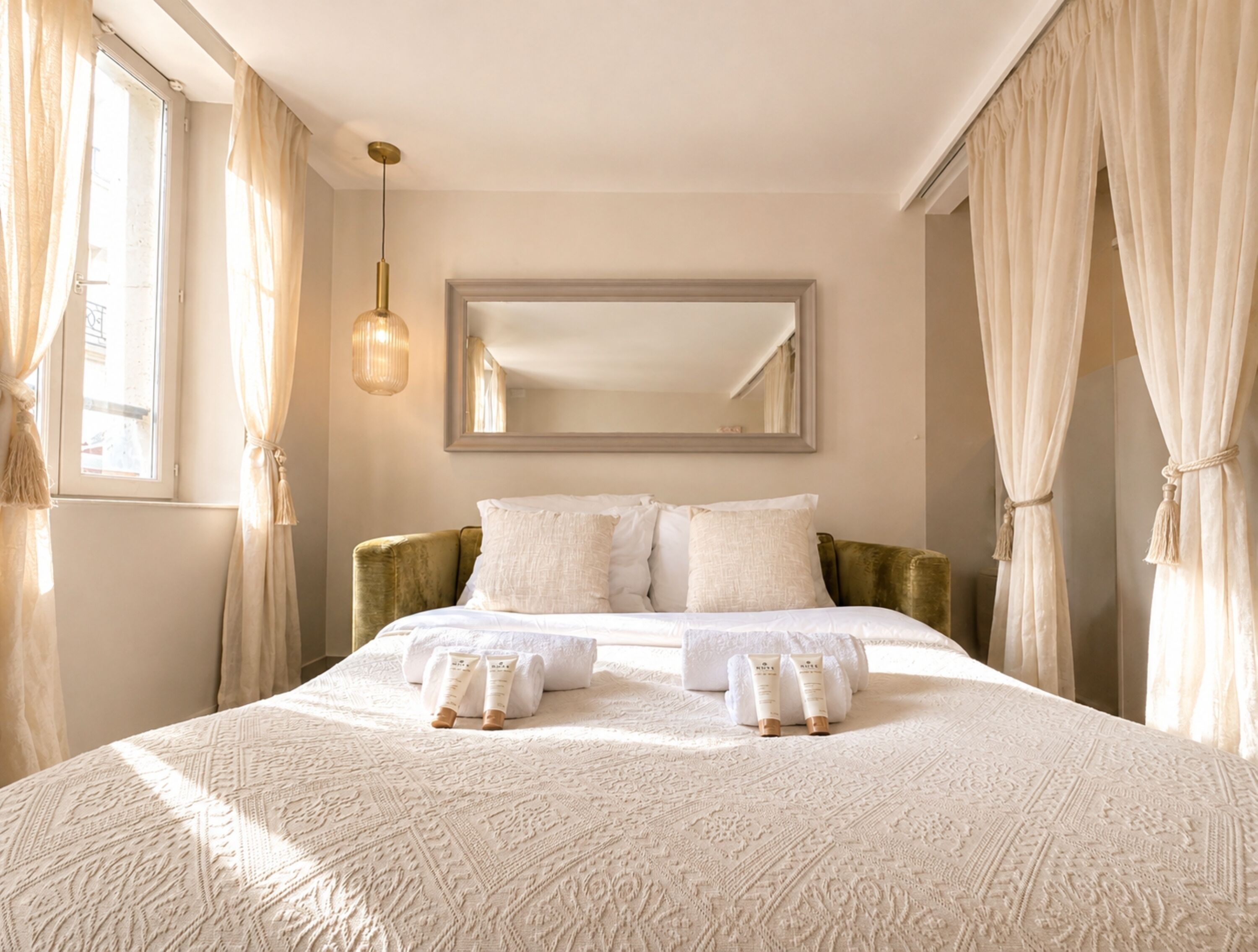 Een hotelkamer met een groot bed, een spiegel en een hanglamp.
