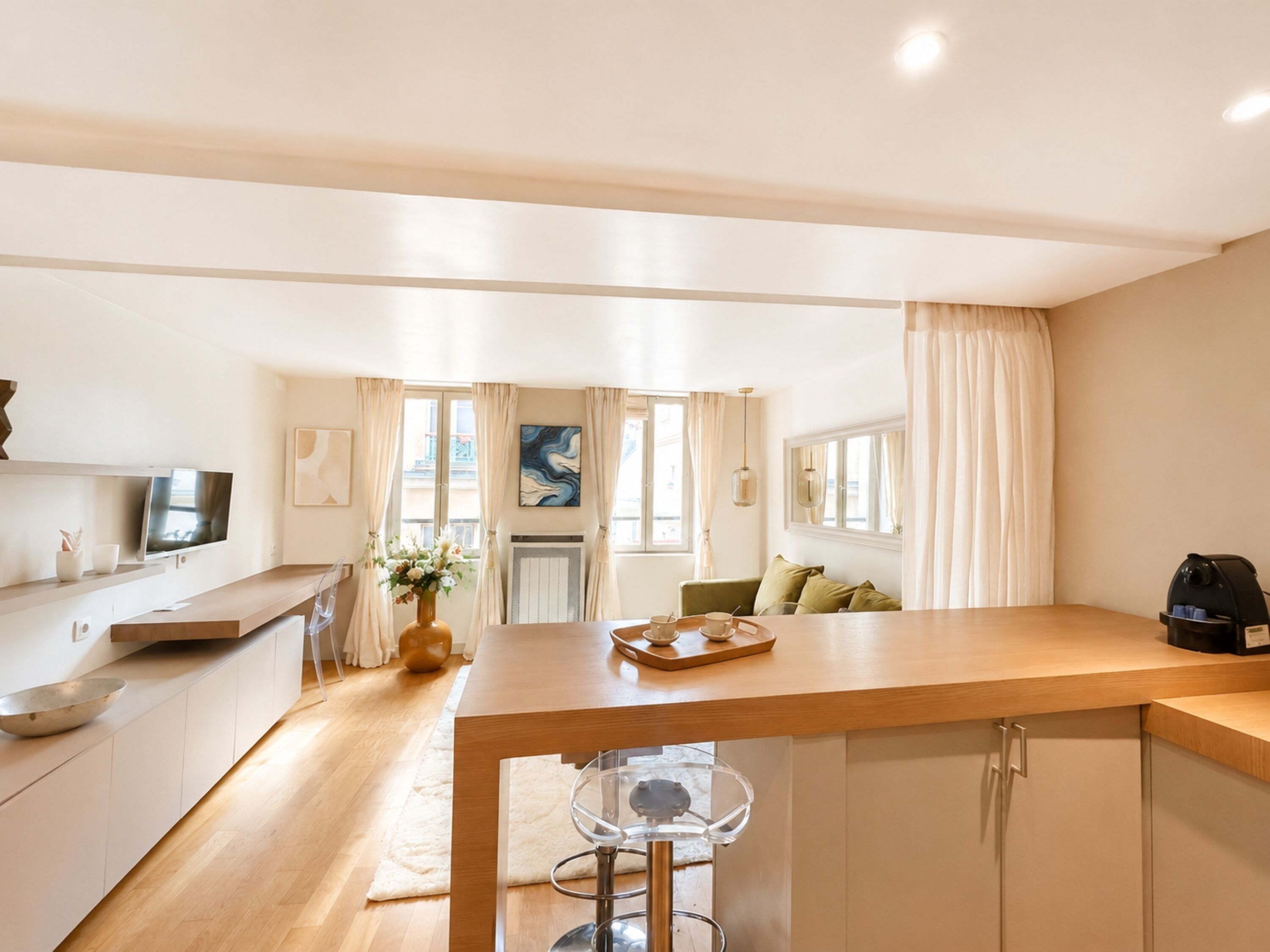Una cocina moderna con encimera de madera, un comedor con mesa y sillas, y una sala de estar con sofá y cafetera.