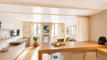 Una cocina moderna con encimera de madera, un comedor con mesa y sillas, y una sala de estar con sofá y cafetera.