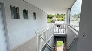 Eine saubere, moderne Treppe mit Metallgeländer, die zu einem Balkon mit Blick auf eine grüne Landschaft führt.