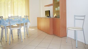 A dining area with a table, chairs, a wooden cabinet, and a clock on the wall. - Comfortable Flat With a Private Courtyard (San Michele al Tagliamento)