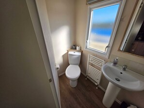 Ein Badezimmer mit Toilette, Heizkörper, Waschbecken und einem Fenster mit Blick.