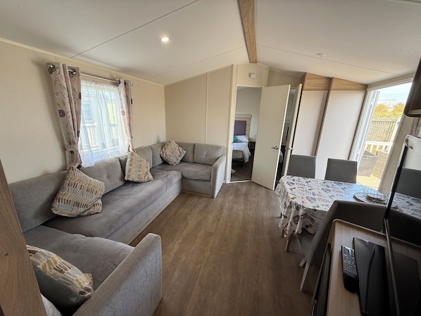 Ein gemütlicher Wohnbereich mit Sofa, Esstisch und Blick durch eine geöffnete Tür.