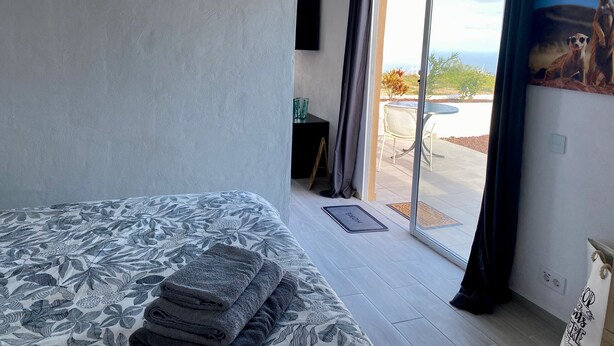 Un dormitorio con cama, vistas al exterior y un comedor.
