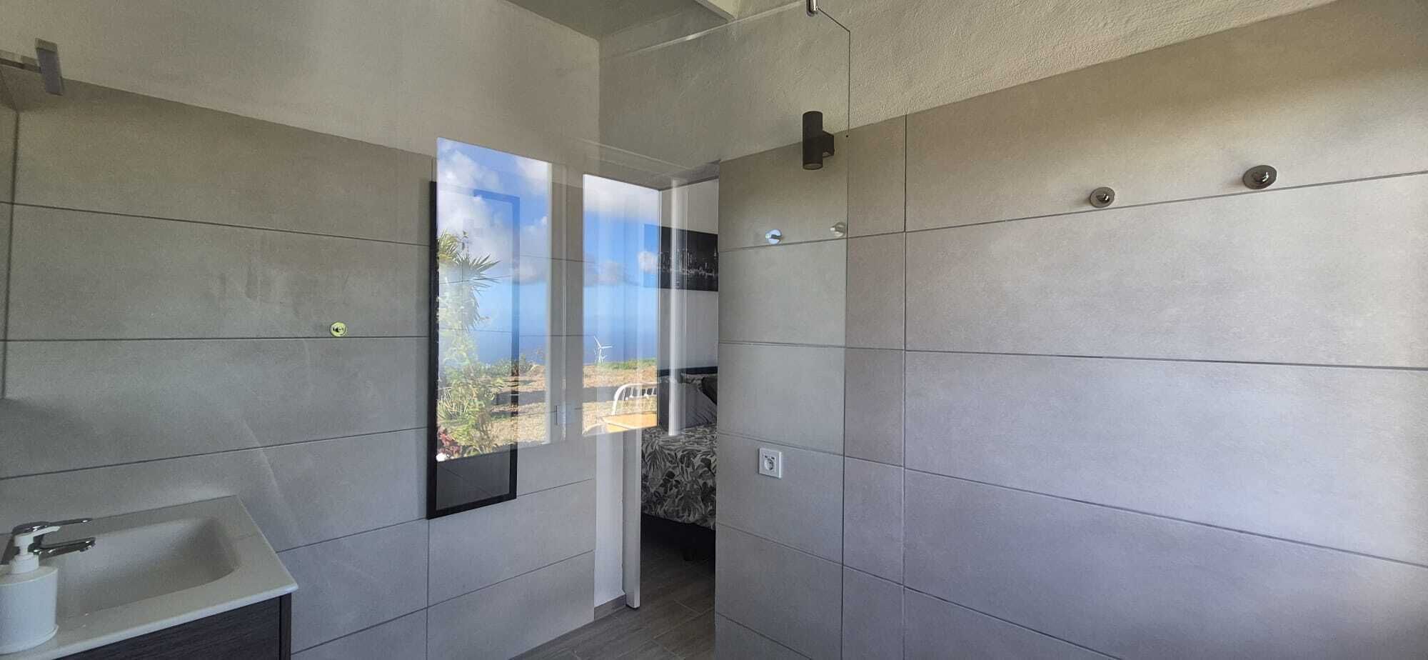 A modern bathroom with a large window, a sink, and a shower area.