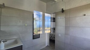 Un baño moderno con un ventanal grande, un lavamanos y una zona de ducha.