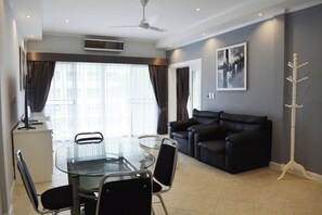 Ein modernes Wohnzimmer mit einem Glastisch, einer schwarzen Ledersofa und einem Garderobenständer.