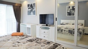 A modern bedroom with a bed, a TV, a desk, and a wardrobe. - Modern Pool-view 1-bedroom Condo With Large Balcony - Baan Suan Jomtien (Pattaya)
