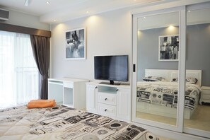 Ein modernes Schlafzimmer mit Bett, Fernseher, Schreibtisch und Kleiderschrank.