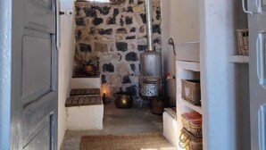 A rustic interior with a stone wall, a metal stove, and shelves with baskets. - Casa Marmoucha View Steppes de l'Atlas Yoga Retreat 11 pers (Aichoune)