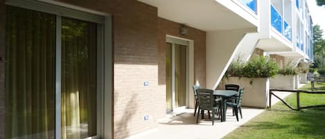 A modern building with a brick facade, large sliding glass doors, and a patio area with outdoor furniture.