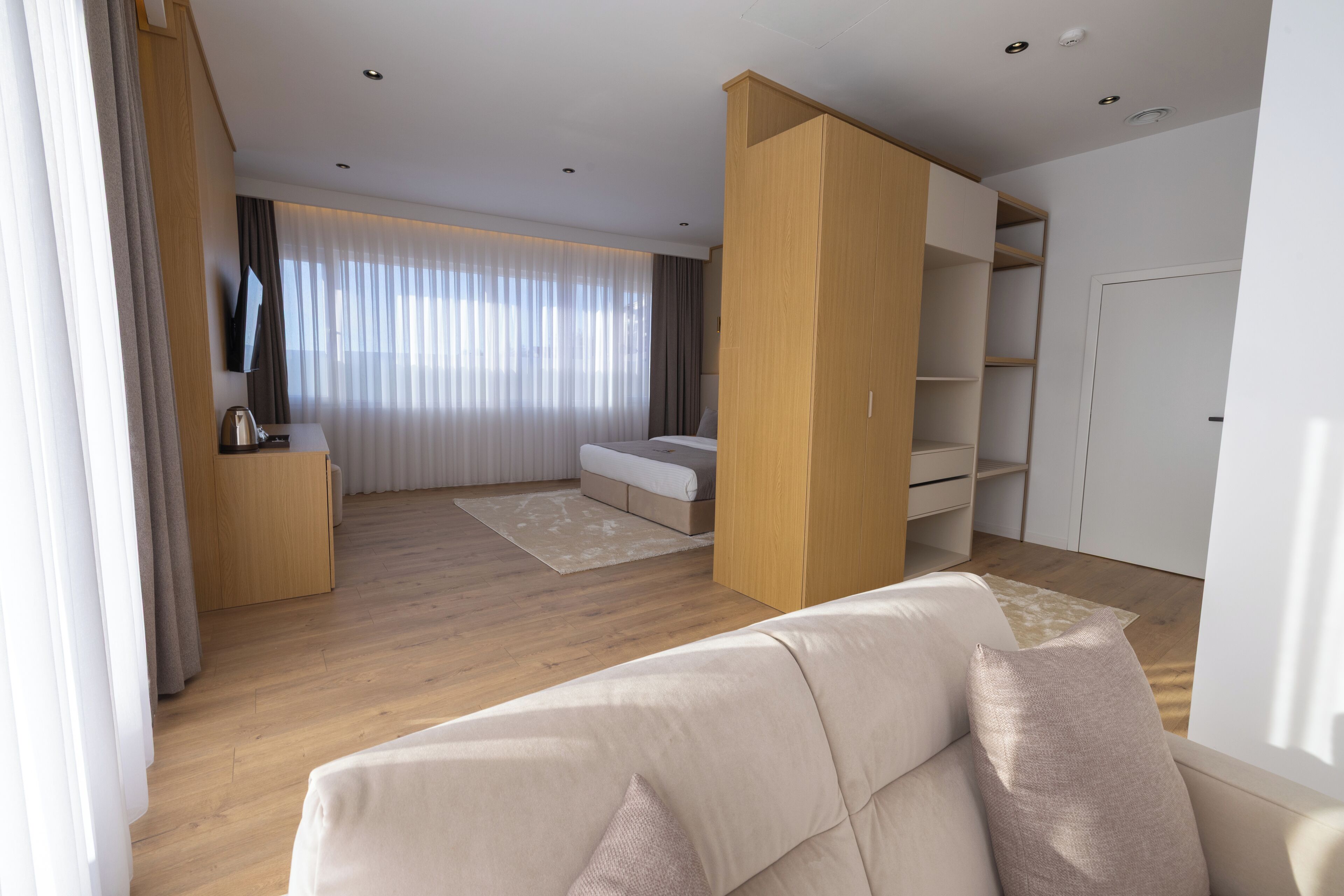 Een moderne woonkamer met een bank, een salontafel, een televisie en een groot raam met gordijnen.