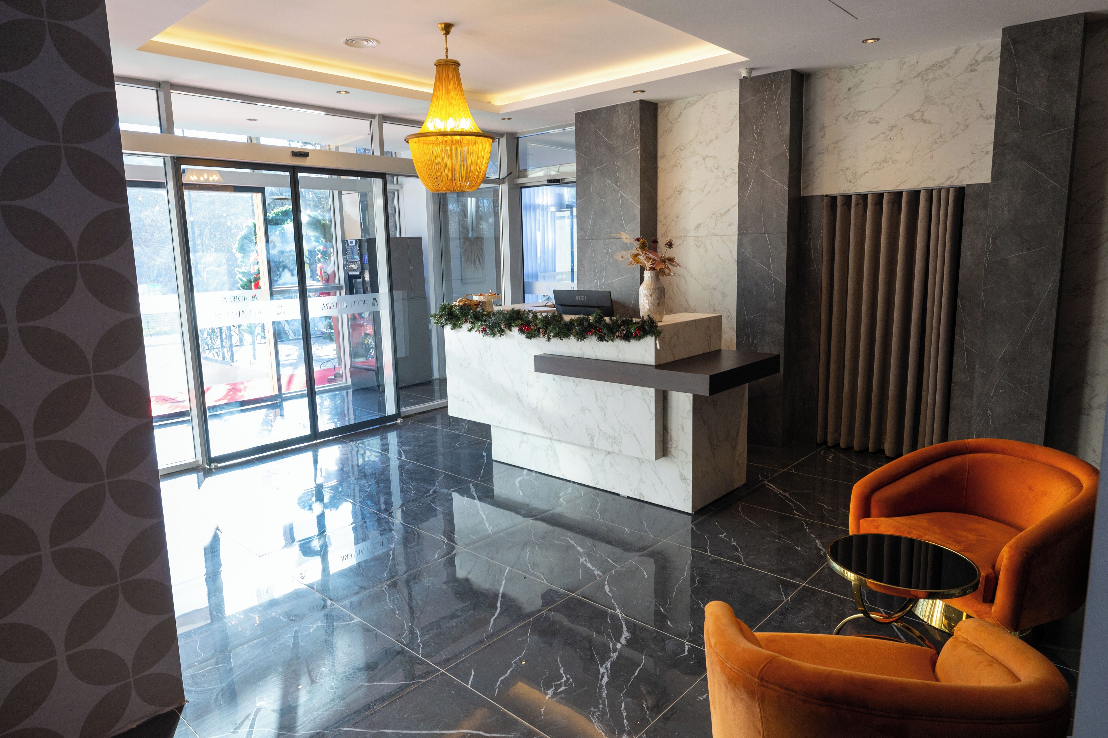 Eine moderne Lobby mit einer Rezeption, einem großen Chandelier und einer Sitzecke mit einem runden Tisch.