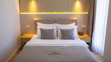Una habitación de hotel con cama, mesitas de noche, teléfono y un logo en la colcha.