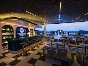 A bar area with a view of the water, checkered flooring, and bar stools. - Victorious Cruise (Tuan Chau)