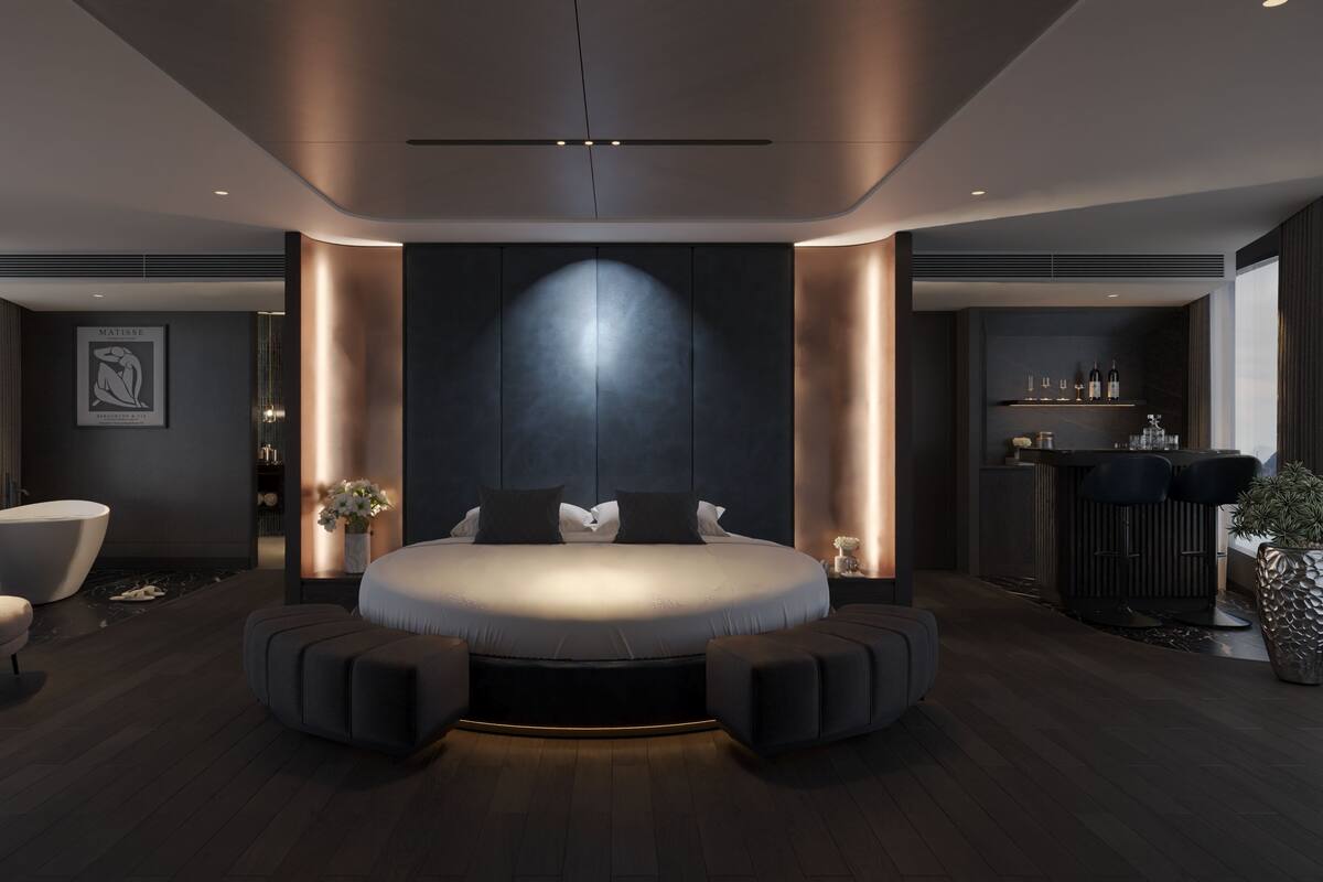 A modern bedroom with a large bed, a seating area, and a bar.