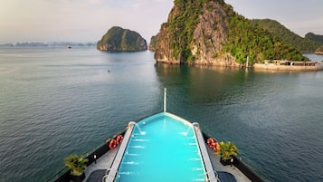 A swimming pool with a view of a large body of water and a prominent island.