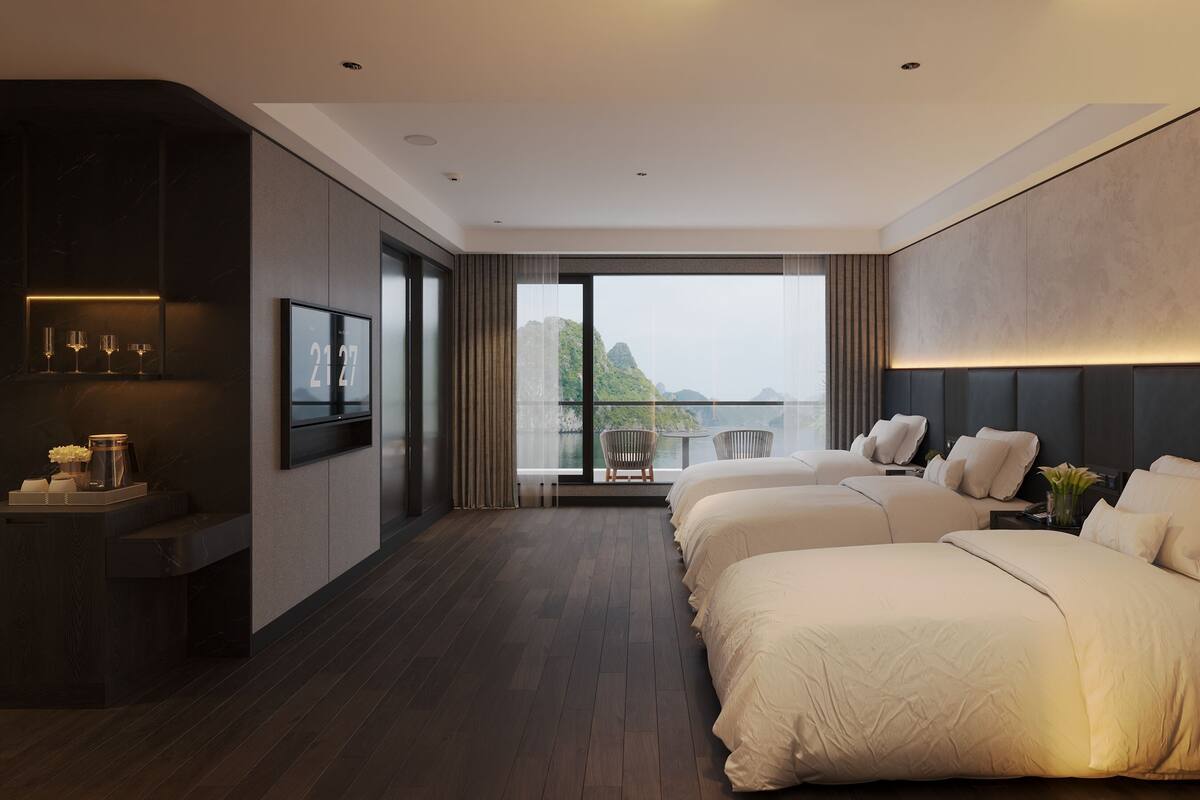 A modern hotel room with a large bed, a balcony with a view, and a minibar.