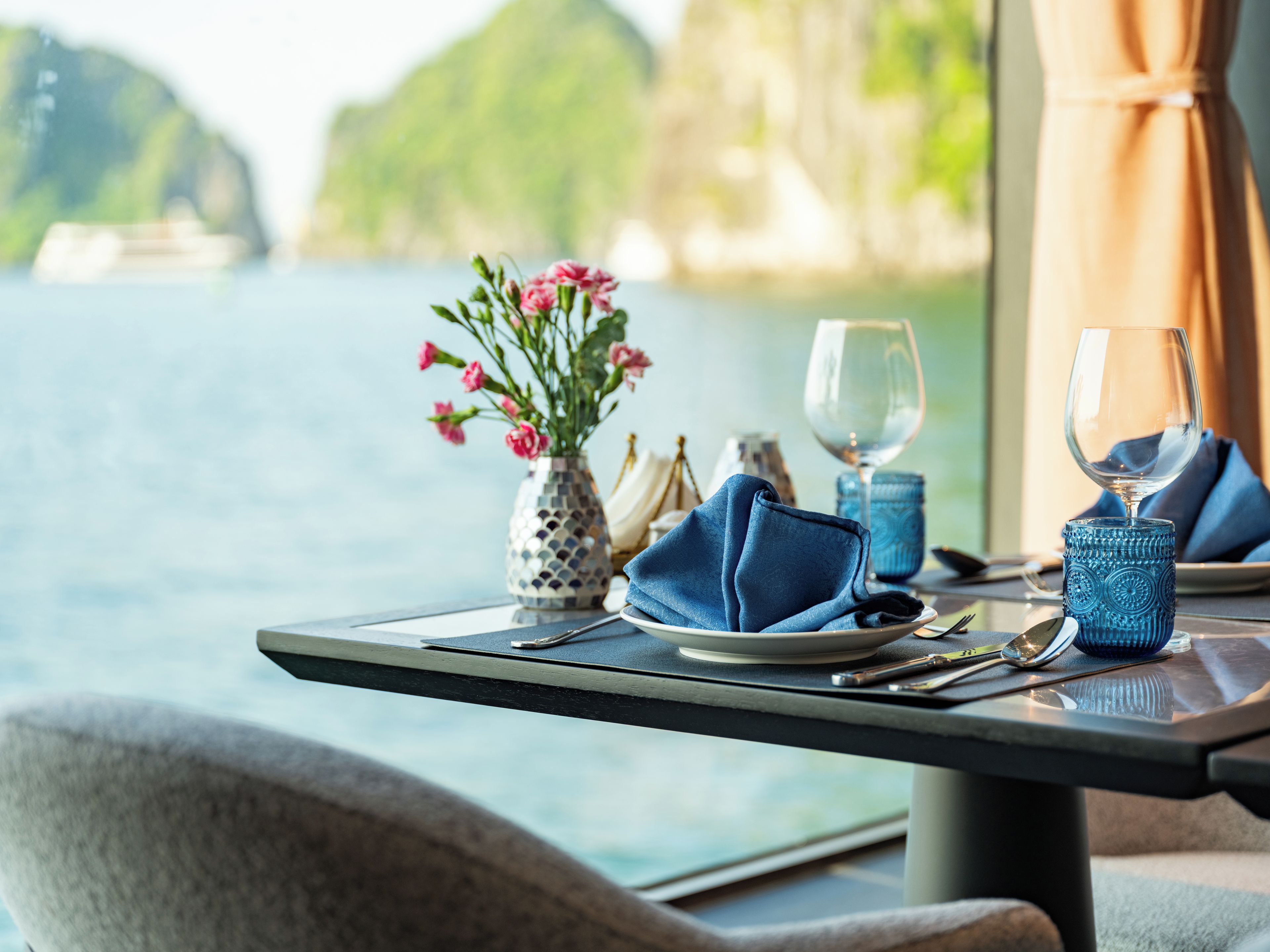 A table set for dining with a vase of flowers, a wine glass, and a napkin.