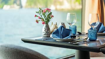 A table set for dining with a vase of flowers, a wine glass, and a napkin.