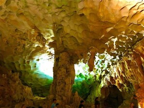 En hule med stalaktitter og stalagmitter, belyst af naturligt lys.