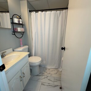 A bathroom with a toilet, sink, and shower curtain. - Ocean Block Condo in North Ocean City (Ocean City)