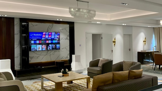 Un soggiorno moderno con una grande TV a schermo piatto, posti a sedere confortevoli e un lampadario.