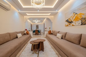 Ein modernes Wohnzimmer mit zwei Sofas, einem runden Couchtisch und einem Essbereich mit Tisch und Stühlen.