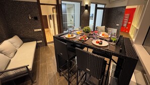 A modern dining area with a black woven table, four chairs, and a variety of dishes and drinks.