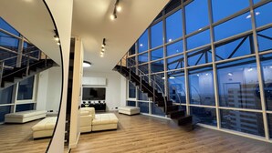 A spacious living area with a large window, a staircase, and a modern kitchen.