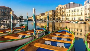 A marina with colorful boats docked, a calm water body, and historic buildings in the background. - Beautiful Mediterranean villa with large pool ideal for families (Villeveyrac)