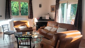 A living room with a brown leather sofa, a glass coffee table, a wooden chair, and a piano. - Beautiful Mediterranean villa with large pool ideal for families (Villeveyrac)