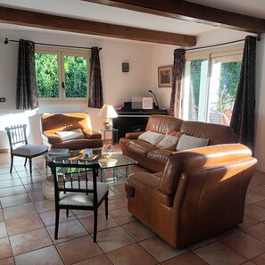 A living room with a brown leather sofa, a glass coffee table, a wooden chair, and a piano. - Beautiful Mediterranean villa with large pool ideal for families (Villeveyrac)