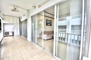 A spacious balcony with a sliding glass door leading to a living area, an air conditioning unit, and a ceiling fan. - Spacious Corner 1-bedroom Condo With 2 Balconies - Baan Suan (Pattaya)