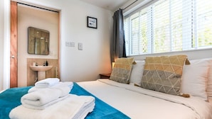 Una habitación de hotel con cama, baño con lavamanos, espejo y ventana con persianas.