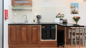 Una cocina compacta con armarios de madera, un lavamanos, una pequeña encimera y una zona de comedor con sillas.