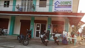 Ein zweistöckiges Gebäude mit einem Schild für CCMPC Accommodation. Vorne sind Motorräder geparkt und eine Person geht auf dem Bürgersteig.