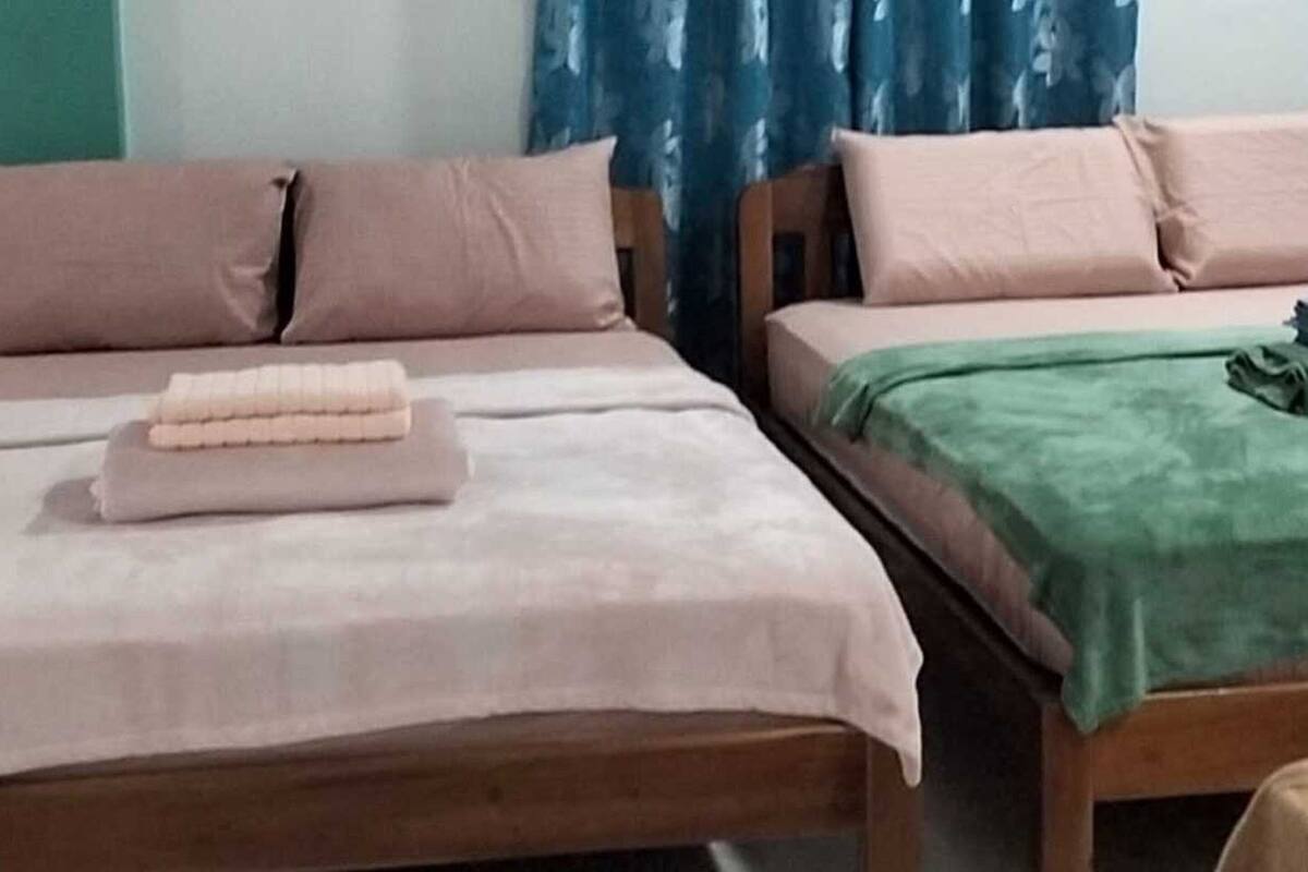 Quarto com duas camas, cada uma com um cobertor de cor diferente.
