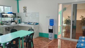 Eine kompakte Küche mit Essbereich, Wasserspender und Blick durch eine Glastür.