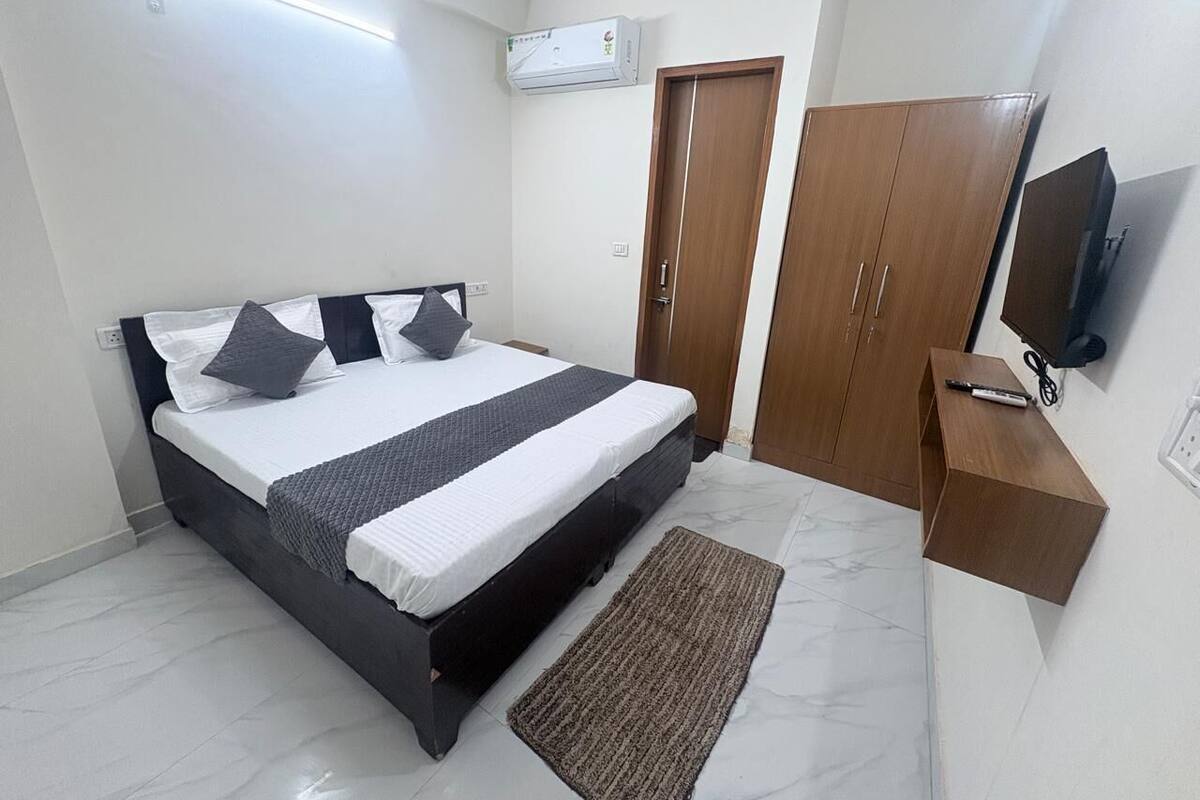 Un dormitorio con cama, armario, televisor y escritorio con silla.
