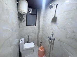Un baño pequeño con inodoro, ducha y un ventanal.