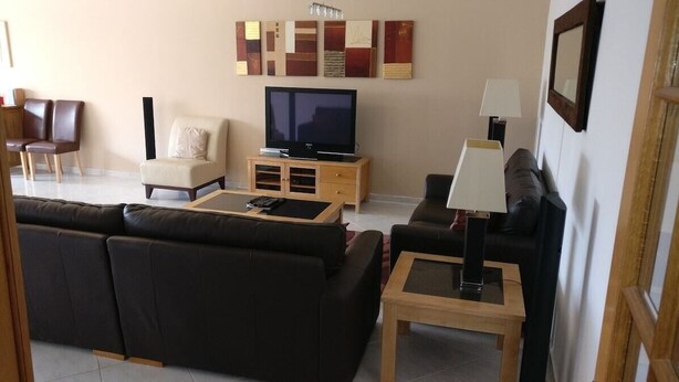 A modern living room with a black sofa, a wooden coffee table, a television on a wooden stand, and a lamp on a side table. - 🏖 Beach Days, Park Views & Easy Living A Perfect Algarve Family Escape (Silves)