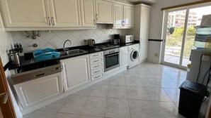 A modern kitchen with white cabinets, a dishwasher, a stove, and a washing machine. - 🏖 Beach Days, Park Views & Easy Living A Perfect Algarve Family Escape (Silves)