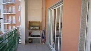 A narrow balcony with a tiled floor, a green railing, and a glass door leading to an interior space with a fireplace. - 🏖 Beach Days, Park Views & Easy Living A Perfect Algarve Family Escape (Silves)