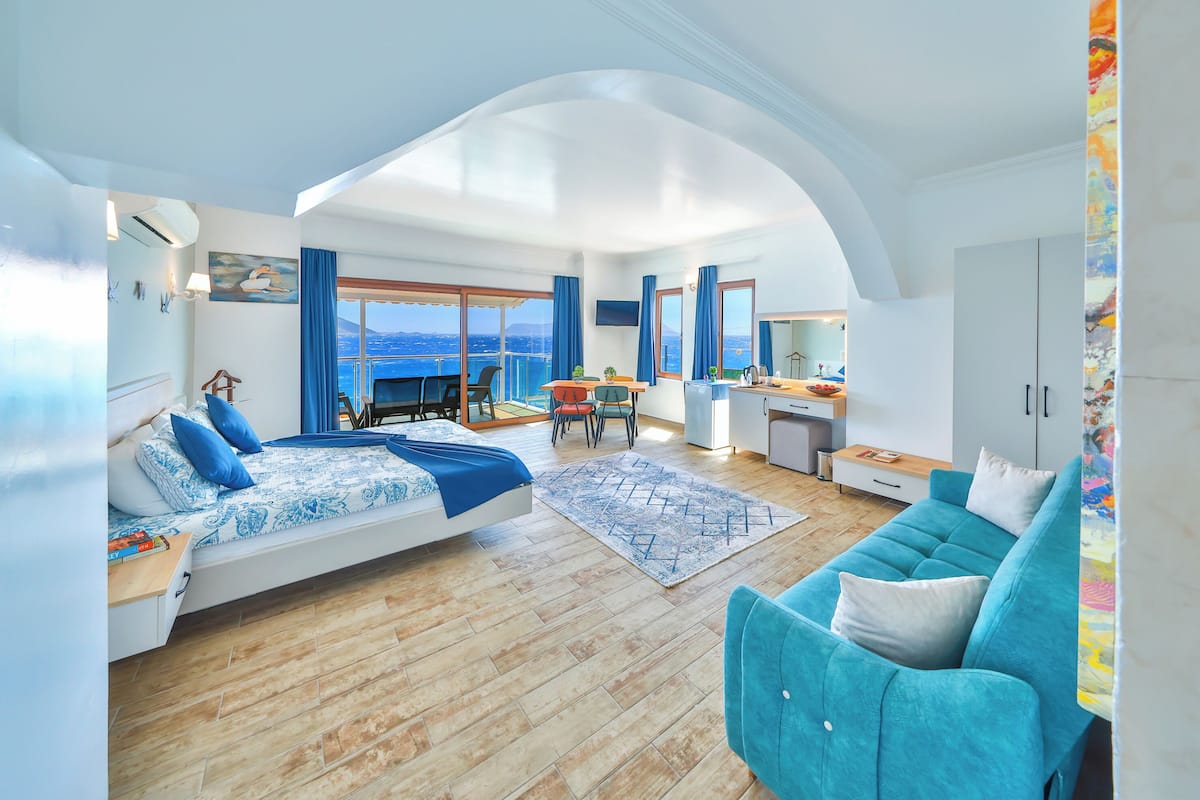 Et moderne hotelværelse med balkon, sofa, spiseplads og tekøkken.