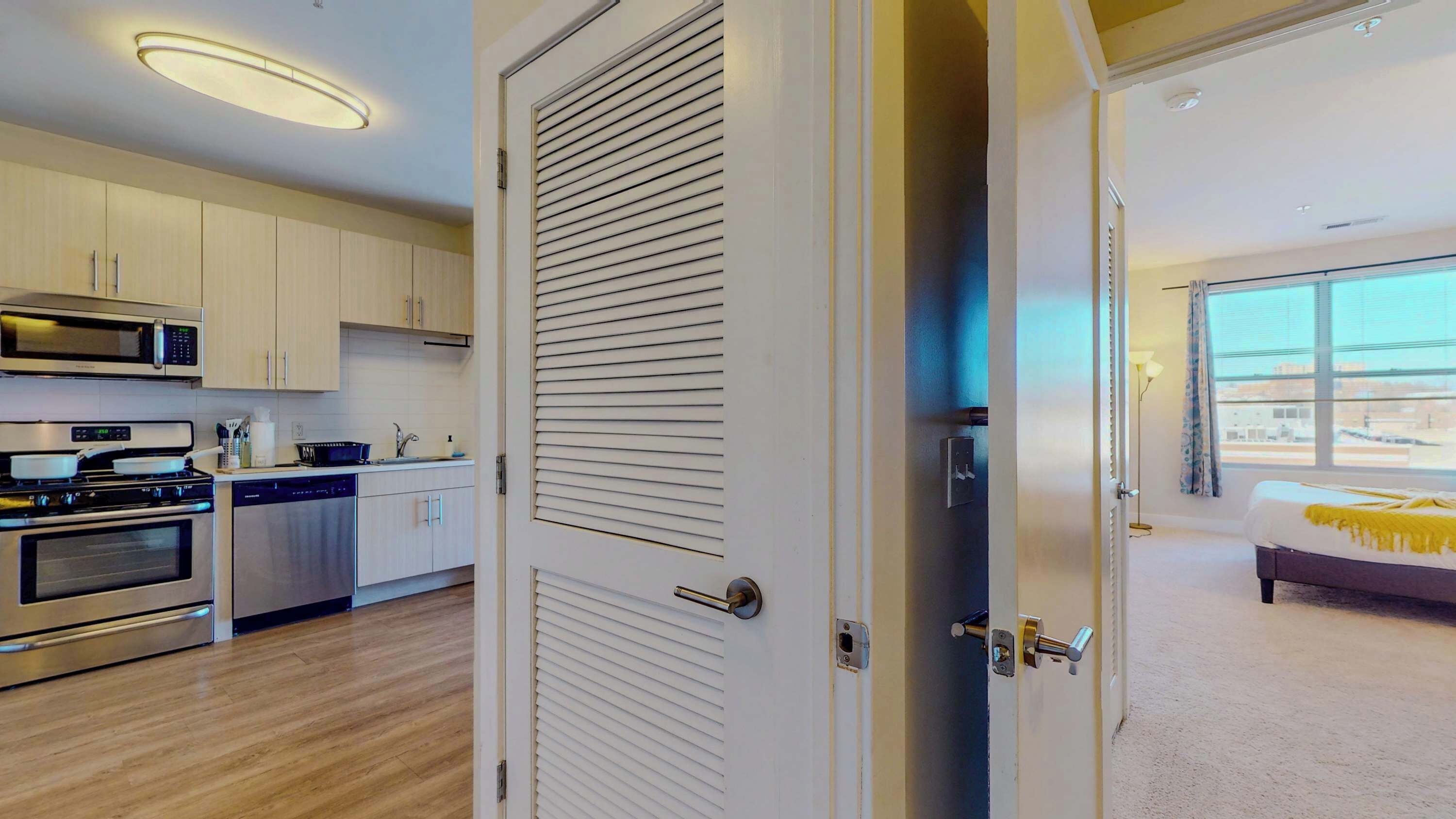 A modern kitchen with stainless steel appliances, wooden cabinets, and a large window.