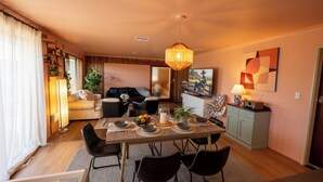 A modern living room with a dining area, a sofa, a coffee table, and a TV. - Little getaway in Spearwood (Spearwood)