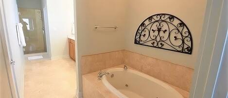 A bathroom with a freestanding bathtub, a shower, and a decorative metal wall piece.